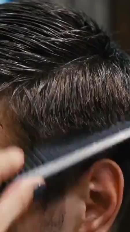 Een barbier werkt een fade bij met de tondeuse