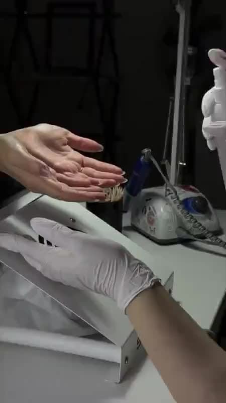 A nail tech filing a new set into shape