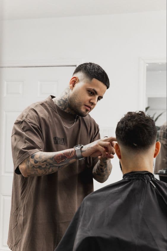 A barber cutting a client's hair in a bright barbershop