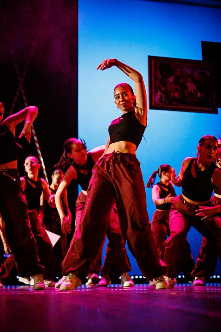 Dansers in een voorstelling op een podium met gekleurd licht