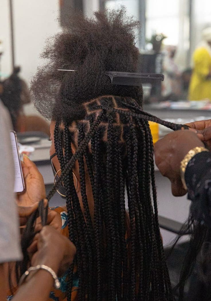 A hairdresser braiding a client's hair in the salon