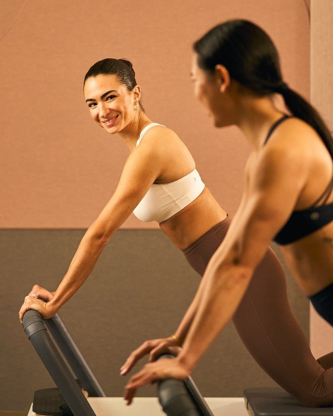 Twee vrouwen trainen lachend op de reformer