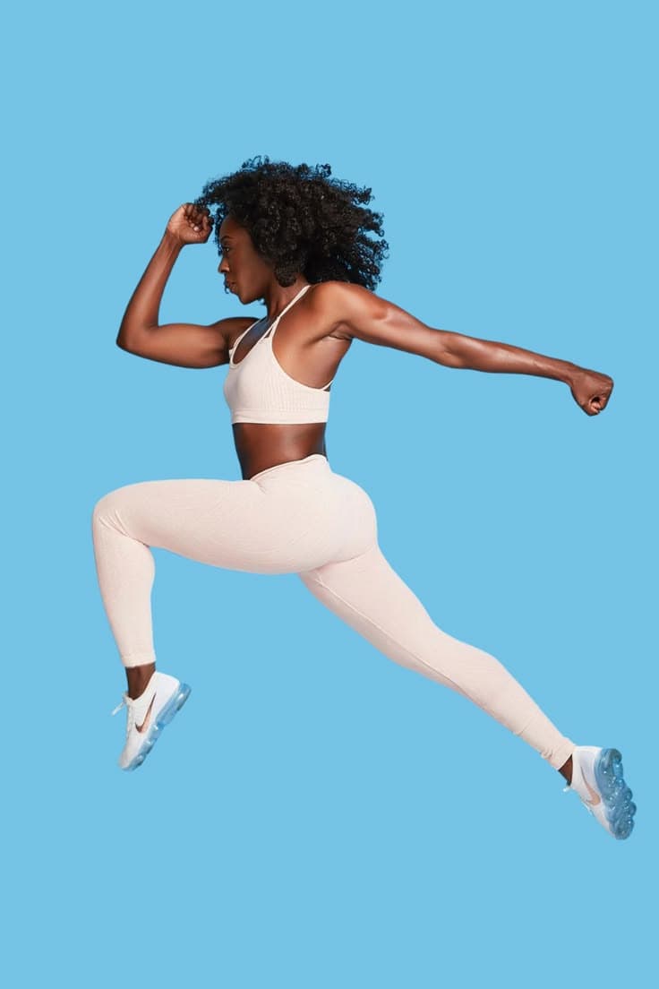 A yoga teacher guiding a pose at the front of the room